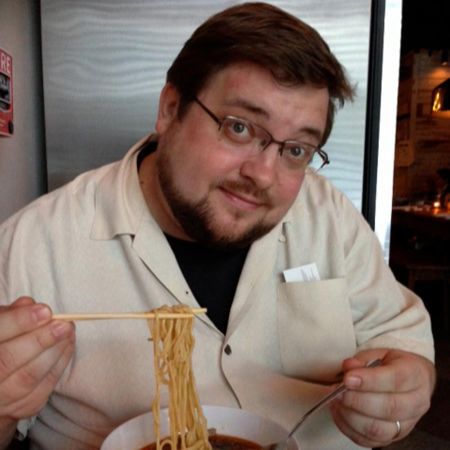 C. B. Cebulski has noodles on a chopstick and a spoon on his other hand.